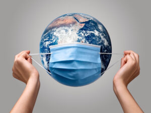 Duas mãos colocando uma máscara no planeta terra simbolizando o cuidado com a covid 19