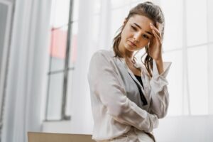 Mulher com a mão no rosto e semblante triste e pensamentos obsessivos