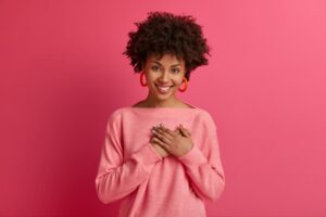 Mulher de rosa com a mão no coração em homenagem ao outubro rosa