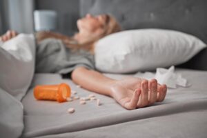 Pensamentos suicidas. Mulher jogada na cama com vários remédio que ela tomou