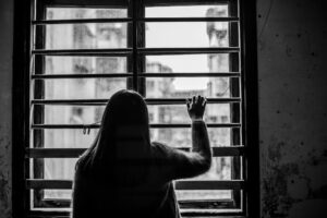 Mulher olhando o tempo chuvoso pela janela com tristeza