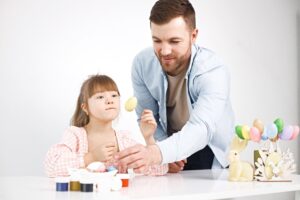 menina com sindrome de down e seu pai brincando com ovos coloridos de pascoa 1